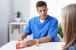 © New Africa - Doctor consulting woman regarding dental implantation at desk in clinic
