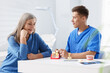 © New Africa - Doctor consulting woman regarding dental implantation at desk in clinic