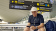 © Nazareno - Senior man waiting at airport terminal using smartphone