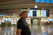 © Nazareno - Senior man traveling in airport terminal looking at departure board