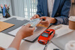 © PHOTO4U - Car purchase transaction with payment, contract signing, key handover, and customer agreement in a modern dealership office, representing automotive sales, business finance, and professional service.