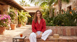 © Chari - Smiling woman sitting cross-legged on a brick bench in a courtyard