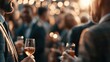 © Oulaphone - People socializing at an indoor party, holding drinks, with warm bokeh lights in the background creating a festive atmosphere.