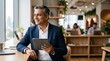 © Eve - Smiling mature South Asian corporate businessman holding digital tablet at office desk. Successful middle aged male entrepreneur working with laptop in modern open space company office.