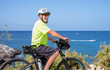 © luciano - Senior man cycling along the ocean on a bright summer day, enjoying an active healthy lifestyle during retirement, wearing a helmet and sunglasses for safety and protection