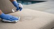 © xuxu - Person in blue gloves cleaning outdoor patio furniture with spray bottle and cloth after a party by the swimming pool