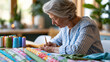 © Nataliya - Faceless senior woman working on craft project at dining table in warmly lit home surrounded by colorful fabric and thread, mature creative hobby concept, lifestyle photography,