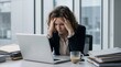 © Rocha Santos - Stressed business woman holding her head in hands suffering from headache or burnout at desk
