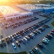 © Raya - Large Organized Car Parking Lot Surrounding Industrial Warehouse at Sunset