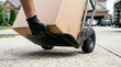 © Mahmuda - professional home moving services | using a hand truck for delivery | mover transporting heavy cardboard box | residential relocation logistics