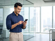 © Someone Cooked Here - Young Indian businessman using smartphone in modern corporate office with copy space for fintech banking technology recruitment communication and business marketing