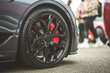 © Pavel Babic - Close-up of a sleek black sports car wheel with vibrant red brake calipers