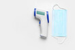 © Pixel-Shot - Medical mask with infrared thermometer on white background