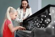 © Pixel-Shot - Young girl playing piano with teacher smiling