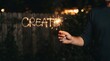 © SimpleDesignStudio - Hand holding a sparkler writing the word create in the air at night for creative inspiration and artistic concept