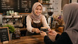 © Dezayn - Muslim Barista Serving Coffee to Customer in Cafe Environment