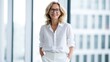 © PixelPulse Creative - Confident professional woman in white business attire standing in a bright office with windows
