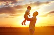 © Faheem art works - Happy father lifting his small young child high into the air during a warm golden sunset