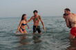 © bernardbodo - Friends laughing splashing in ocean water enjoying summer vacation