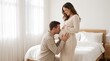© Faysal - Father Kissing Pregnant Belly While Expectant Mother Smiles at Home