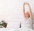 © Prostock-studio - Good rest. Cheerful well-slept senior lady stretching in bed in morning, empty space