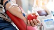 © inthasone - An individual contributing to a blood donation drive while grasping a red heart shaped stress ball representing the significance of donating blood and the essence of generosity in a medical environmen