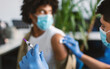 © Prostock-studio - Clinical trial for new modern vaccine during global pandemic. Guy in medical face mask getting injection at hospital. Doctor preparing syringe to give a shot, rubbing arm with cotton pad