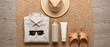© Kassiopeia  - Sunglasses, a straw hat, sandals, a linen shirt, and sunscreen are arranged neatly on a woven mat. This scene shows preparation for a sunny day outdoors
