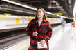 © JackF - Girl standing at metro stop, subway station platform, waiting for transport. She carefully reads signs and looks for required metro train departure platform.