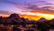 © lalinan - A vibrant sunset paints the sky with hues of purple, pink, and orange over a rugged mountainous landscape.