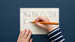 © Mr Andrian - Close up of child hand practicing writing alphabet letters on lined paper with pencil