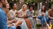© MT - Diverse group of young adult friends laughing and drinking hot beverages around a backyard fire pit during a cozy autumn evening gathering