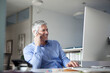 © Westend61 - Businessman sitting at desk, talking on the phone