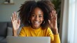 © Petro - A joyful Black girl with curly hair raises her hands in excitement while video chatting from her cozy living room.