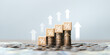 © Wachirapong - A wooden block image with percentage (%) symbols stacked on a pile of coins, with an upward-pointing arrow, reflects effective financial planning and increasing interest.