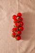 © ShapeImages - Fresh red cherry tomatoes on the vine lying on textured linen tablecloth