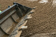 © kalyanby - Mini loader levelling quartz sand surface on equestrian arena outdoor horse riding ring footing installation and maintenance process