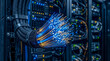© Marina - A bundle of high-speed glowing fiber optic cables transmitting blue and orange data signals in a server data center.