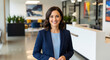 © Fine Craft - Portrait of a confident and elegant businesswoman in a blue suit standing in a modern office, representing corporate leadership