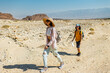 © zhukovvvlad - A boy with a backpack and a map walks next to his mother through the desert. Family trekking. Timna National Park. The child is actively spending time.