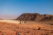 © zhukovvvlad - A mother and child on a hike. A boy with a map and a backpack walks next to his mother. Family trekking. Timna National Park. The child is actively spending time.