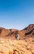 © zhukovvvlad - Two active backpackers stroll through the desert against a blue sky. Mother and child on a hike. Summer camp. Timna National Park. The child is actively spending time.