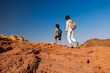 © zhukovvvlad - A boy with a backpack and a map walks next to his mother through the desert. Family trekking. Timna National Park. The child is actively spending time.