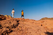 © zhukovvvlad - A boy with a backpack and a map walks next to his mother through the desert. Family trekking. Timna National Park. The child is actively spending time.
