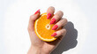 © Suratama - Woman hand with colorful chevron nail art holding a fresh orange slice on white background.