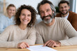 © lashkhidzetim - Warm smiles fill this friendly, collaborative scene. Two people sit together, hands resting on a document. Their joyful expressions suggest mutual trust and satisfaction. The setting implies teamwork