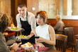 © JackF - Polite young waiter presenting fresh salad plates to a young couple in a cozy restaurant