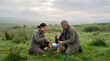 © Rendara Studio - Two field researchers examining soil samples in a remote grassland at dawn