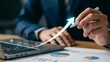 © Soyaeb - Businessman analyzing statistics on laptop with graphs and upward trend arrow