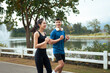 © PaeGAG - Young asian couple exercising together while jogging outdoors in park